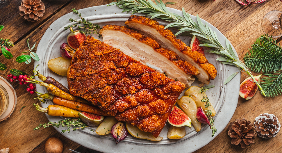 roast pork belly with crispy crackled skin served with roasted baby carrots, potatoes, onions and butternut squash