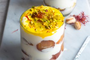 indian dessert parfait layered with gulab jamun and yoghurt, and topped with saffron milk mixture, chopped pistachios and saffron.