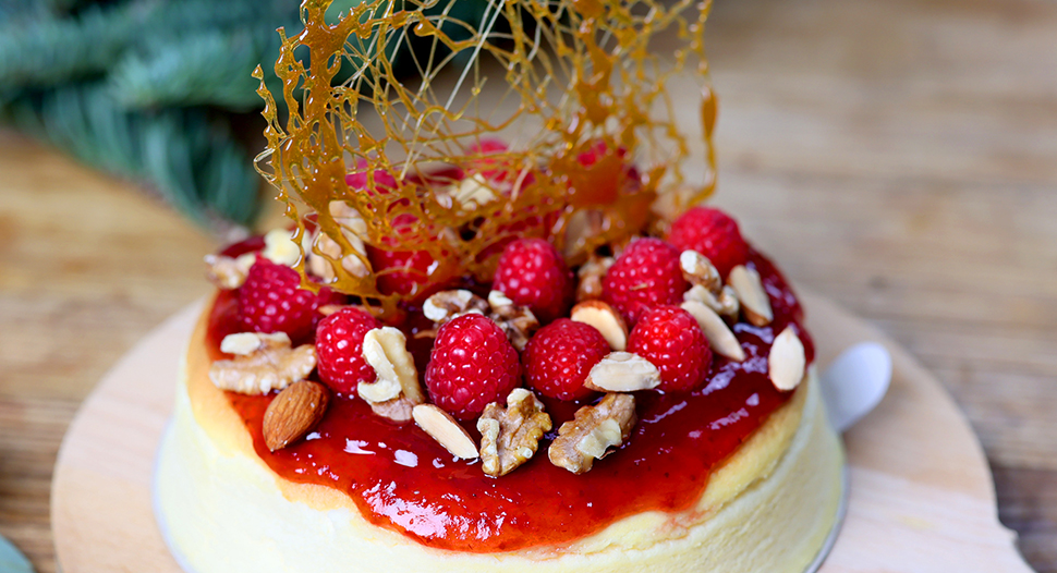 christmas cheesecake topped with strawberry jam, candy, mixed nuts and sliced raspberries and strawberries