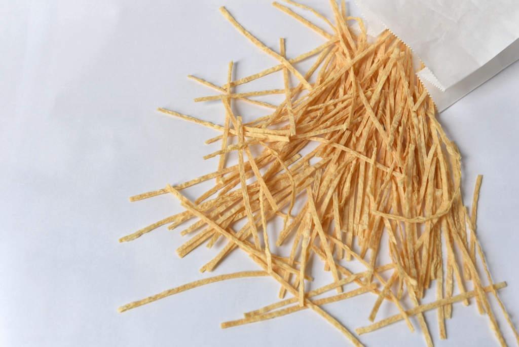 Long strips of dried fish fillet snack arranged artfully on a light-coloured background