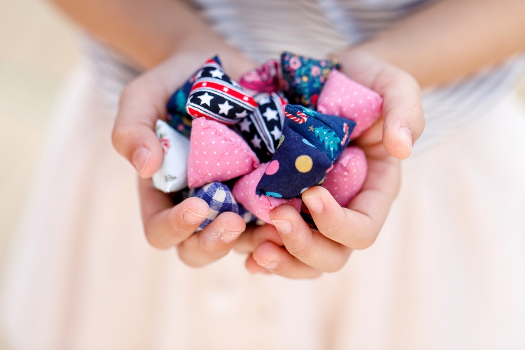 Close up of a girl's hands holding a bunch of colourful five stones