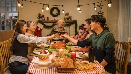 An Asian family in a dining room toasting wineglasses over a Christmas feast
