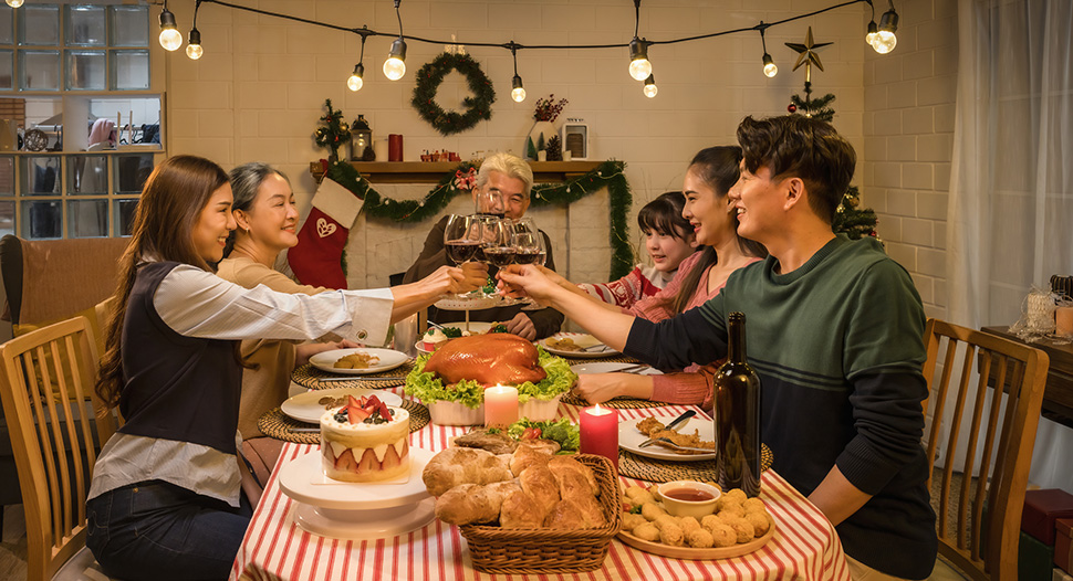 An Asian family in a dining room toasting wineglasses over a Christmas feast